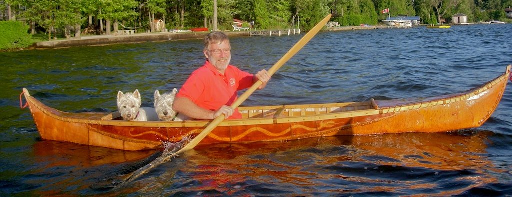 Man paddling a canoe-kayak with two dogs